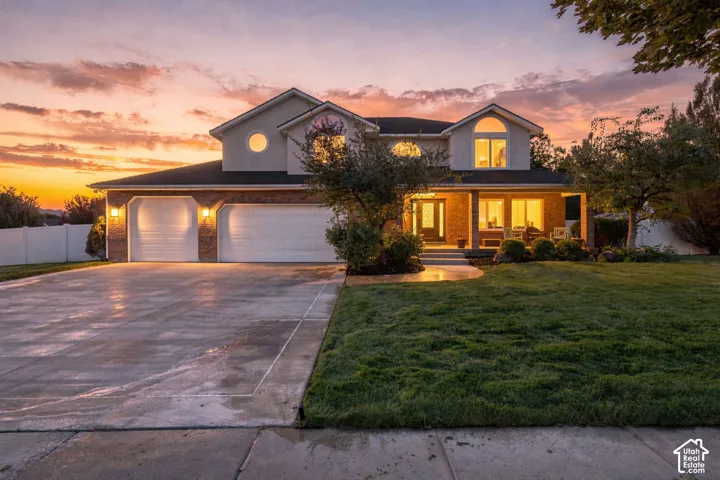 Brick and siding exterior with a covered front porch, concrete driveway, and attached two-car garage