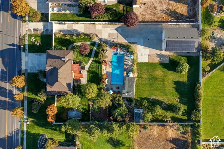 Expansive property featuring a private swimming pool, mature landscaping, paved driveway, detached structure with solar panels, and a substantial grassy area