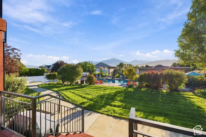 Expansive backyard featuring a manicured lawn, paved pathways, and a swimming pool with a slide