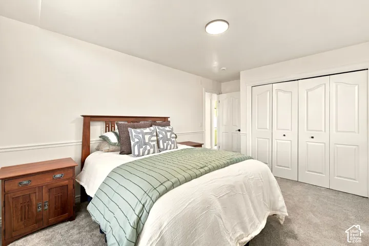 Recessed ceiling light, crown molding, paneled bifold closet doors, wood-finish headboard, and gray carpeting