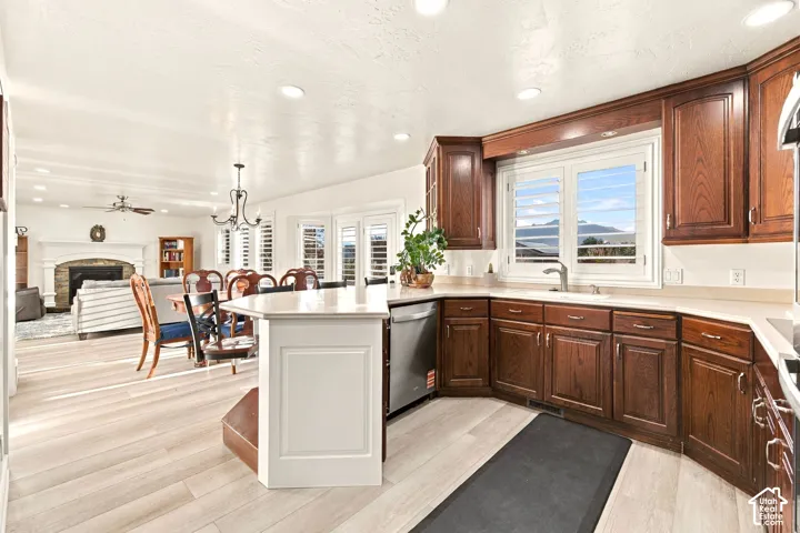 Kitchen featuring wood-finish cabinetry, light countertops, and a stainless steel dishwasher