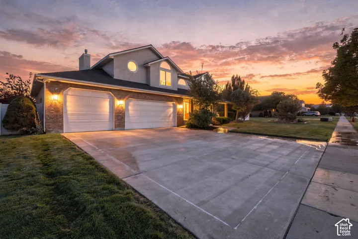Two-car garage with individual doors, stone-accented facade, concrete driveway, and front lawn