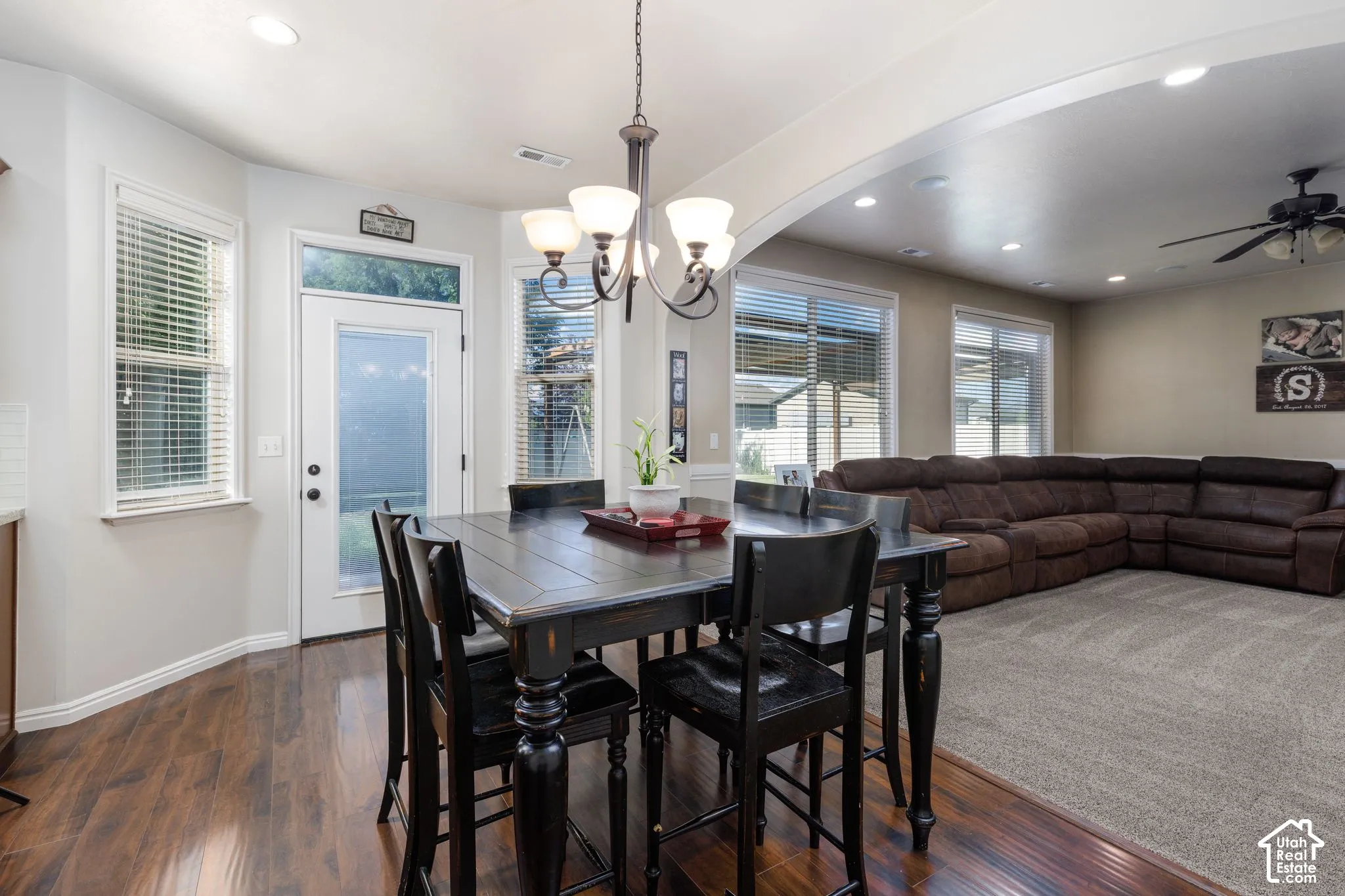 Wood-finish flooring in the dining area, arched entryway, recessed lighting, ceiling fan, and sliding glass door