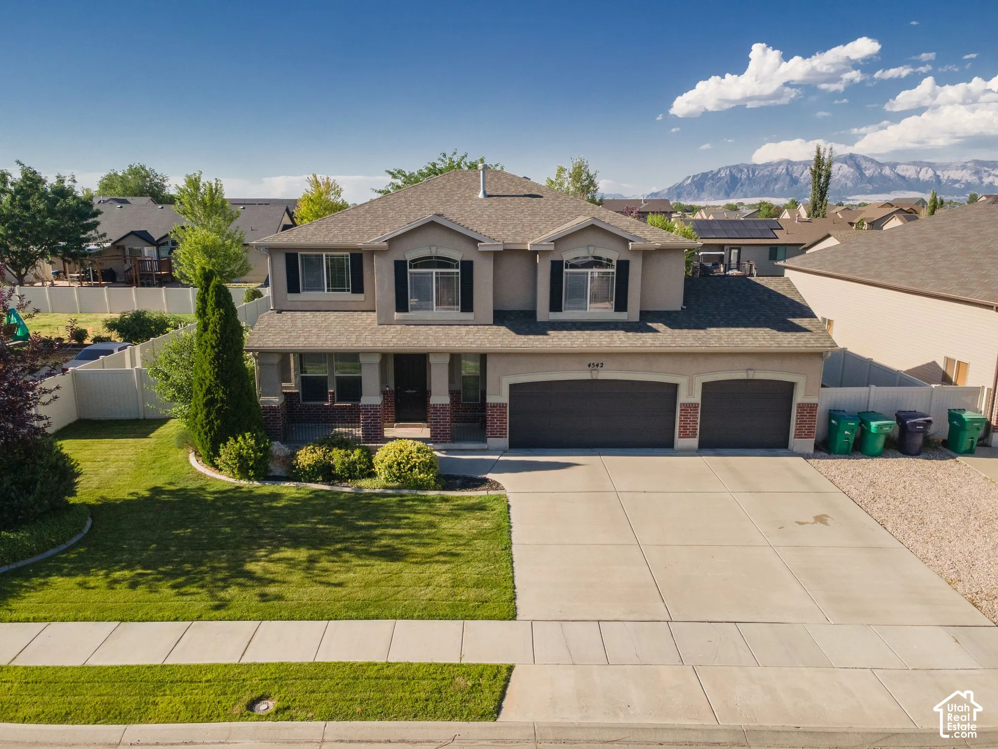 Two-story residence featuring a two-car garage, established front landscaping, and a covered porch entry
