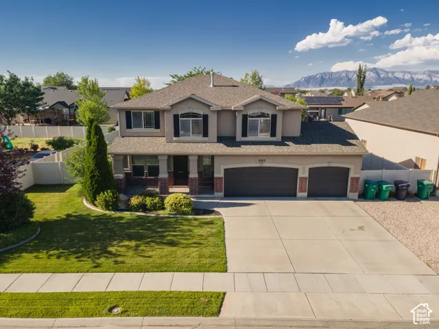 Two-story residence featuring a two-car garage, established front landscaping, and a covered porch entry