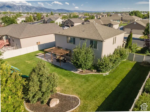 Expansive backyard featuring a manicured lawn, paved patio with pergola, and mature landscaping