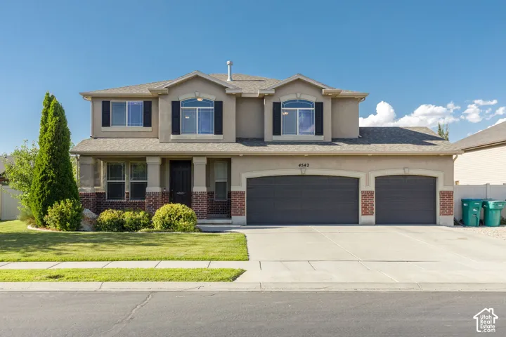 Two-story stucco and brick-front residence with a two-car garage, covered porch entry, and arched garage doors