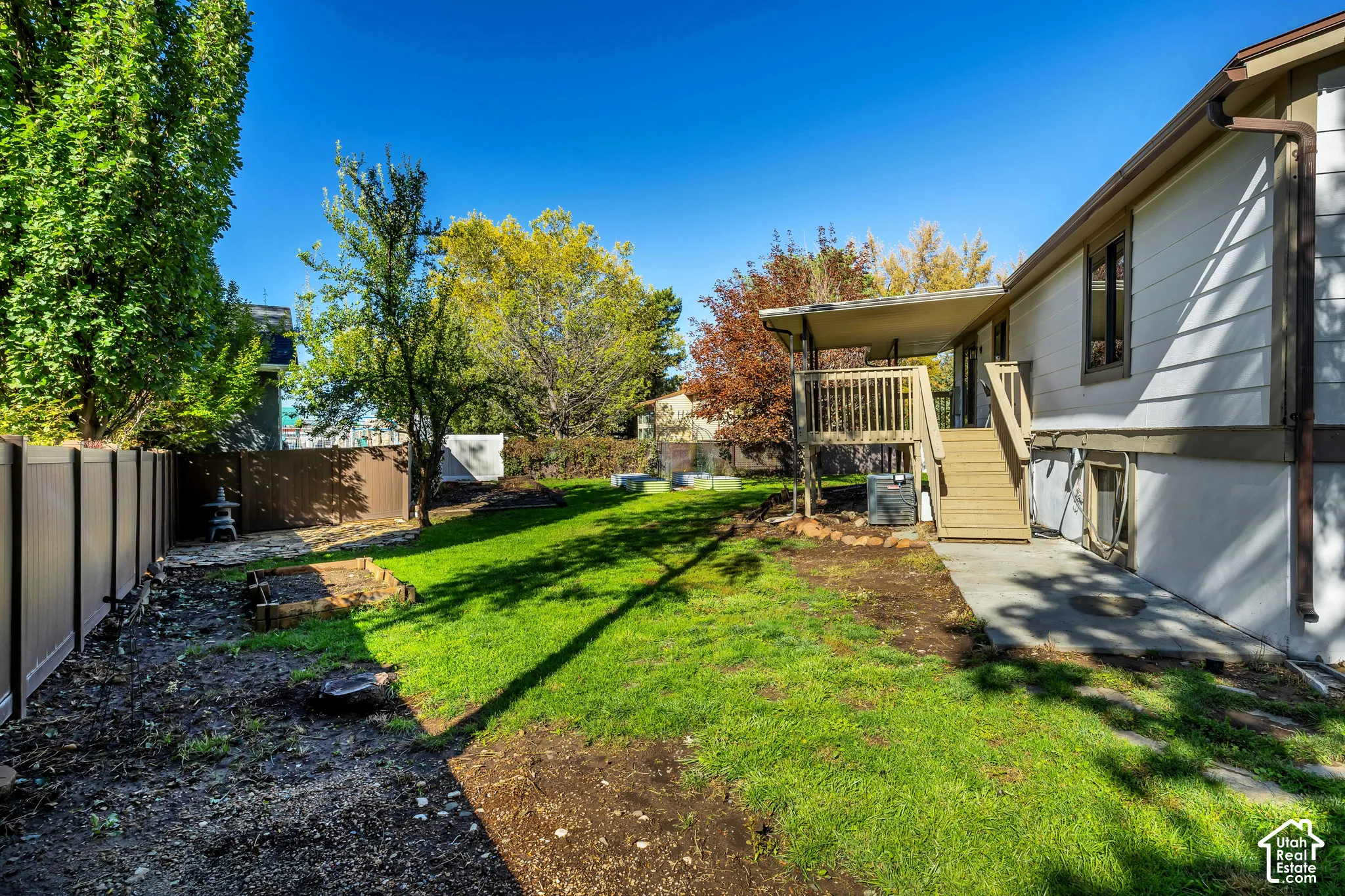 Expansive backyard featuring a lush lawn, privacy fencing, and an elevated wood deck with stairs