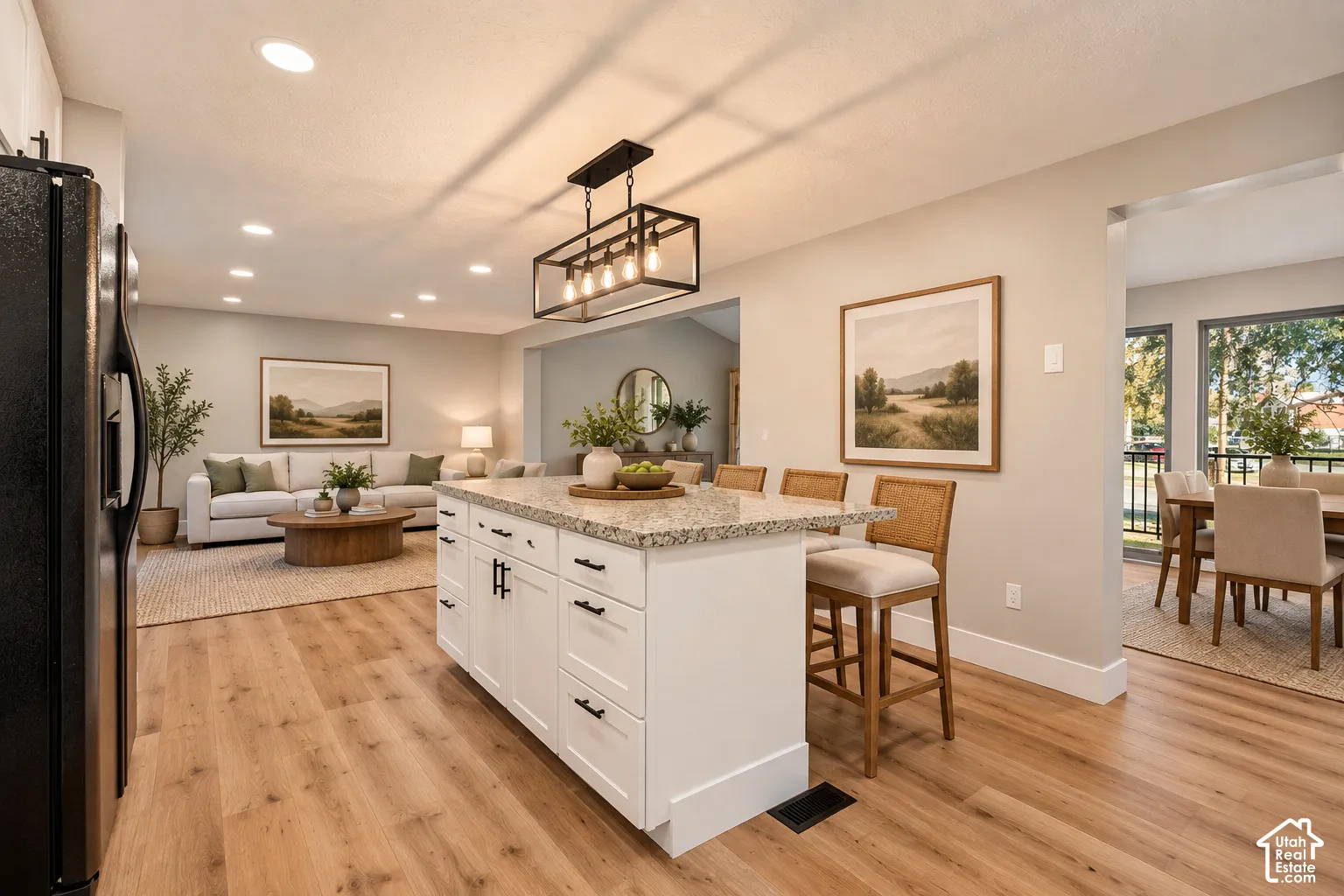 Kitchen island with granite countertop, recessed lighting, wood-finish flooring, white cabinetry with dark hardware, and a modern chandelier