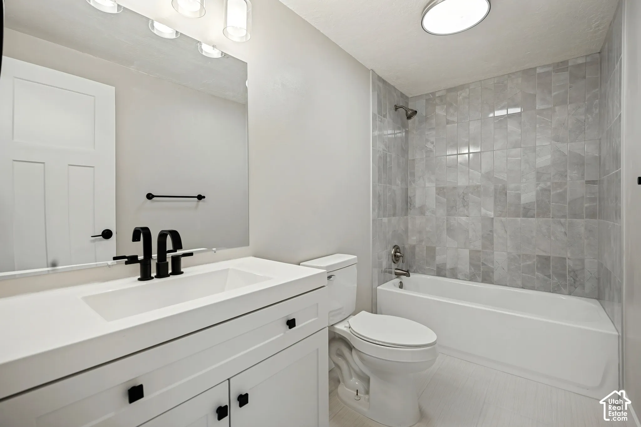 White vanity with integrated sink, black fixtures, and a large mirror