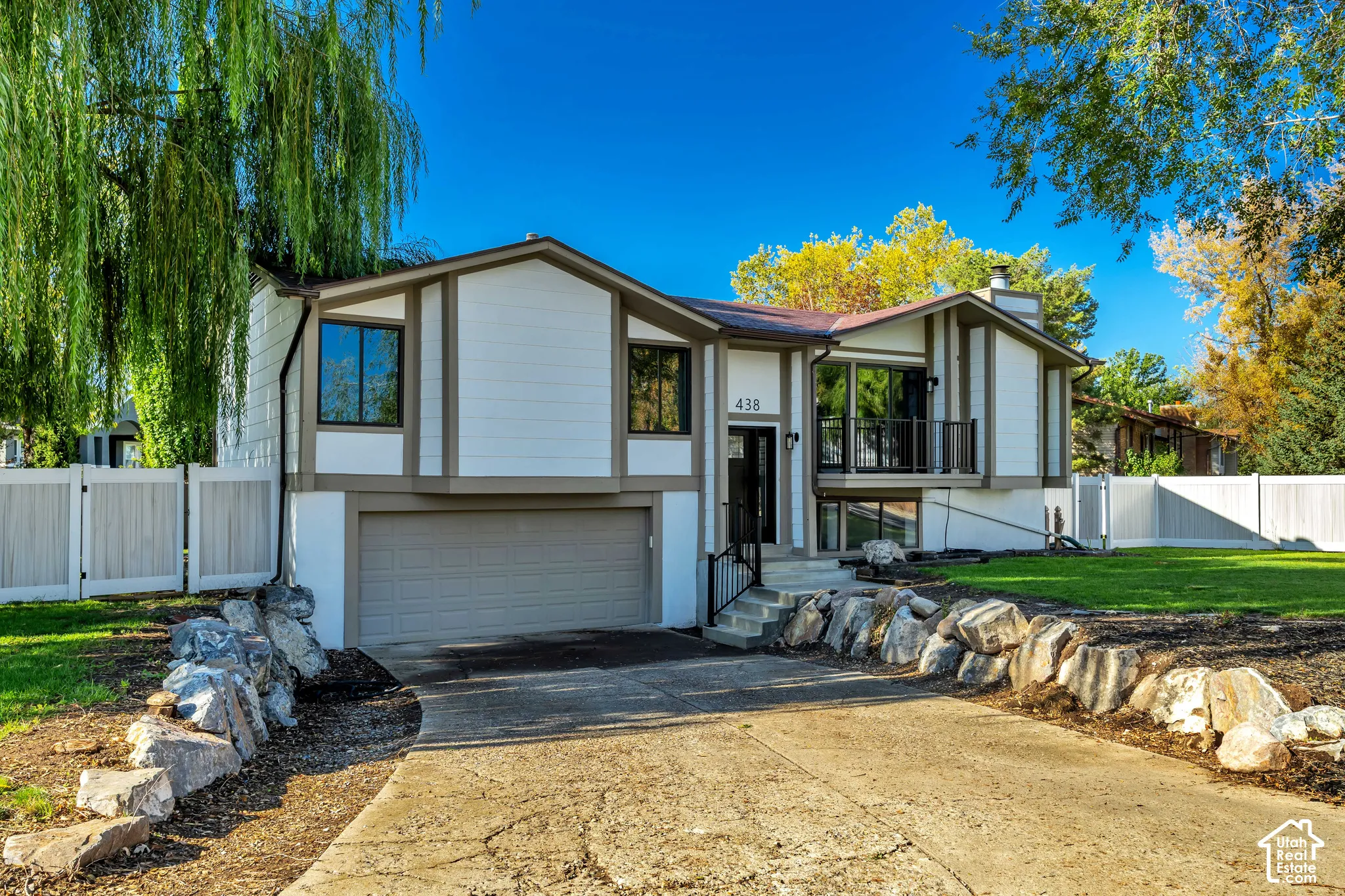 Split-level residence featuring a two-car garage, white siding, dark trim, and a prominent front entrance