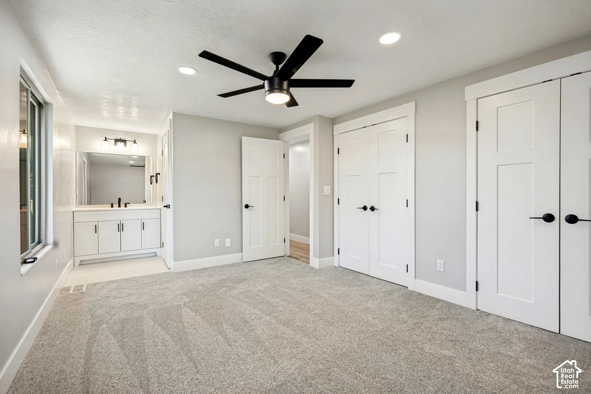 Recessed lighting, ceiling fan, grey wall paint, two paneled doors, and light grey carpeting