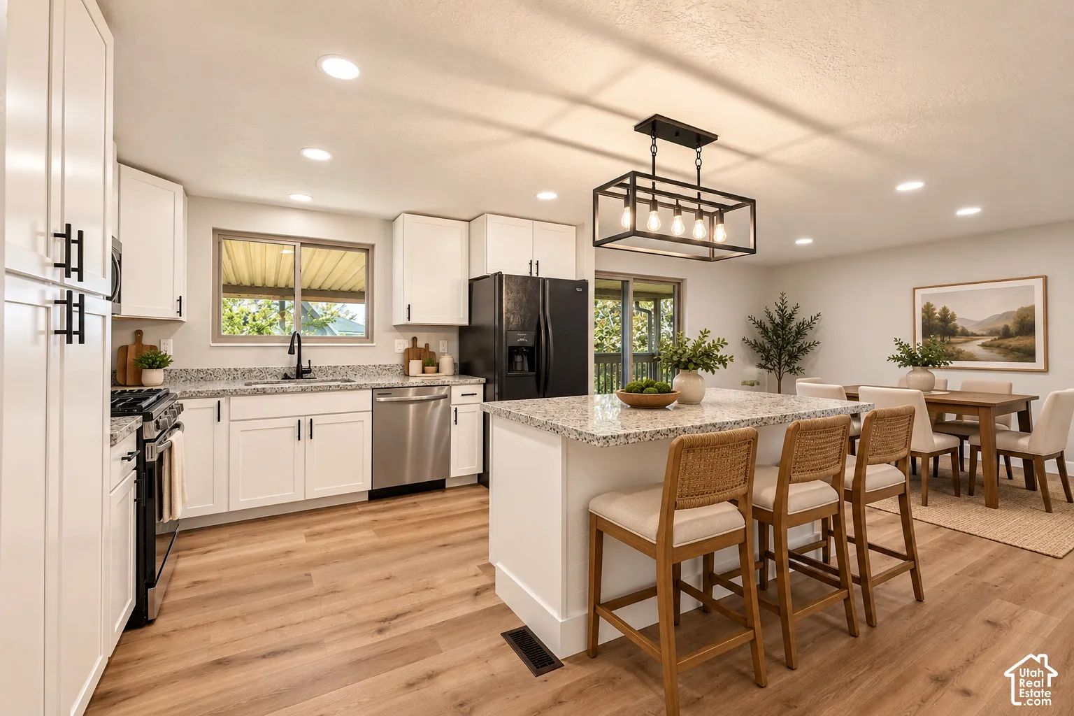 Kitchen featuring white cabinetry, granite countertops, wood-finish flooring, stainless steel appliances, and an island with seating