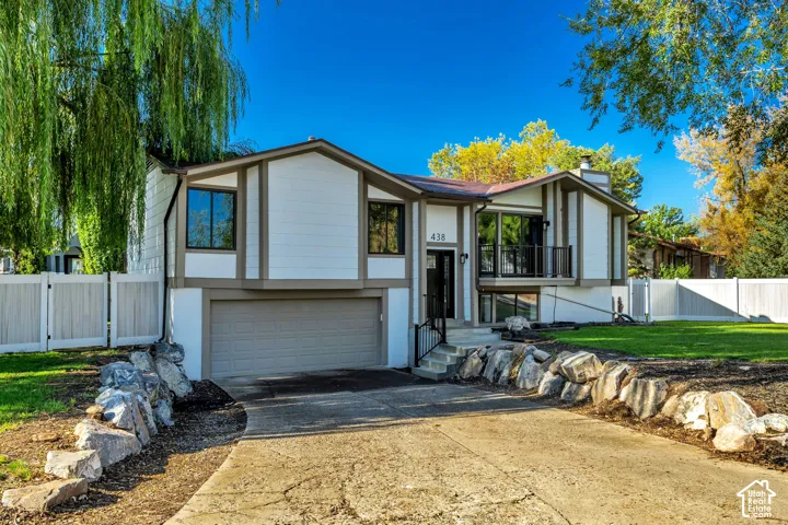 Split-level residence featuring a two-car garage, white siding, dark trim, and a prominent front entrance