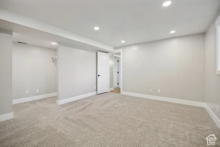 Spacious room with plush carpeting, recessed lighting, white trim, and a white interior door