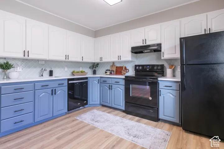 Two-tone cabinetry with contrasting hardware, white countertops, tile backsplash, wood-finish flooring, and black appliances