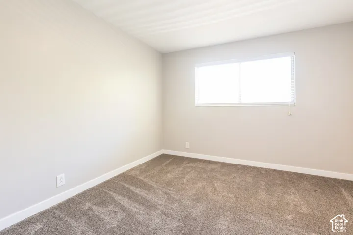 Neutral wall tones, installed carpeting, white window blinds, and white trim accents