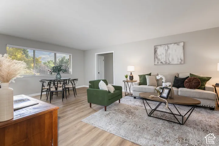 Wood-finish flooring throughout, light gray wall paint, and a large window with horizontal blinds