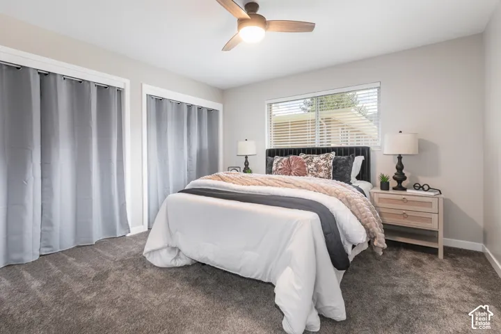 Recessed window with blinds, dual closet spaces with curtain coverings, and a ceiling fan with integrated lighting