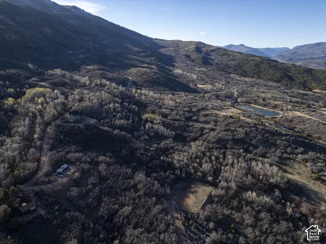 Expansive mountainous terrain with wooded areas and a visible body of water