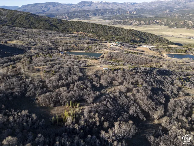 Mountainous terrain with natural vegetation, multiple ponds, and distant structures