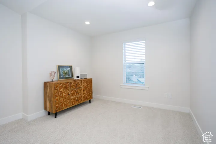 Recessed lighting, light-toned carpeting, white walls, and a window with blinds