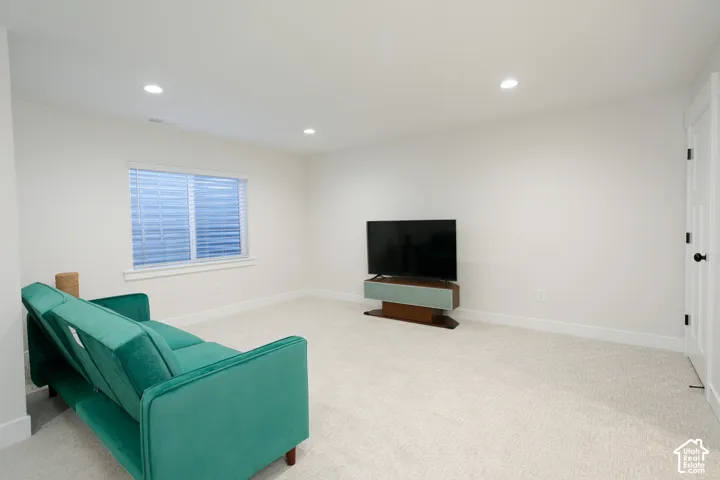 Recessed lighting, light-toned carpeting, white walls, and a white window frame with blinds