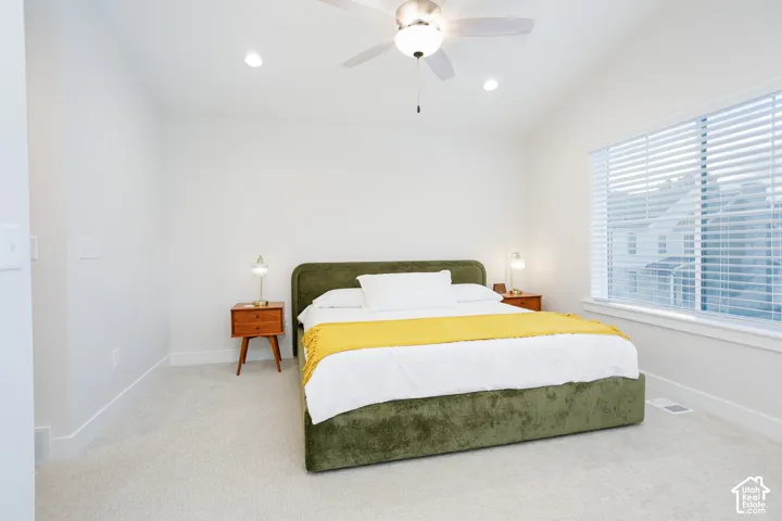 Vaulted ceiling, ceiling fan, recessed lighting, large window with blinds, and light-colored carpeting