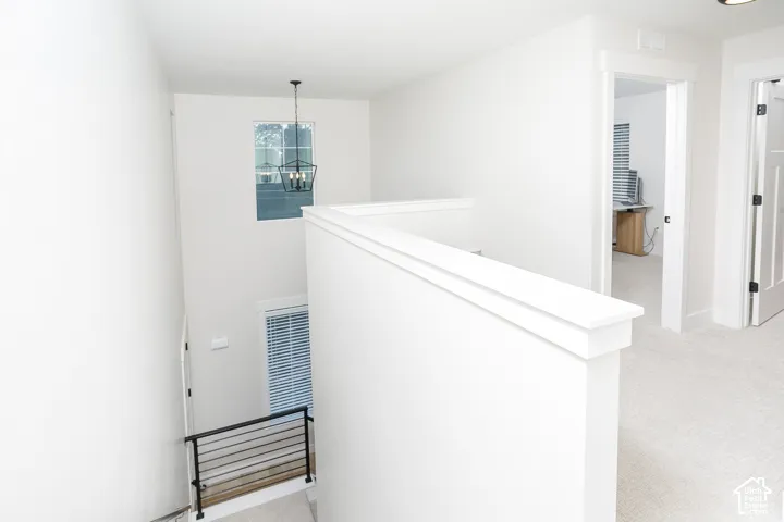 Open hallway with white walls and light-colored carpet