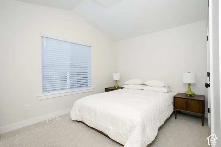 Vaulted ceiling, wall-to-wall carpeting, and window with blinds
