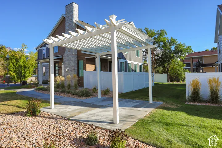 White pergola over a concrete patio, a gravel bed, and a manicured lawn