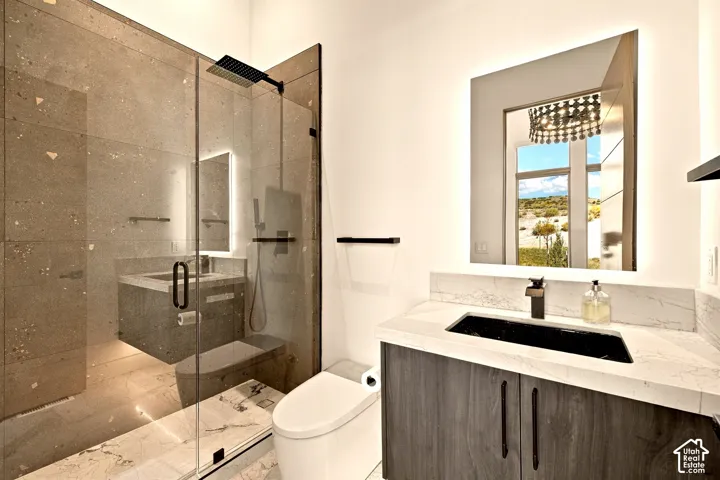 Glass-enclosed shower with a rainfall showerhead, stone-finish wall tile, and marble-finish flooring