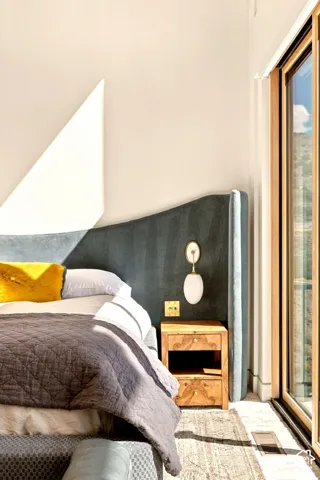 Floor-to-ceiling sliding glass door, wall-mounted sconce lighting, and wood-finish flooring