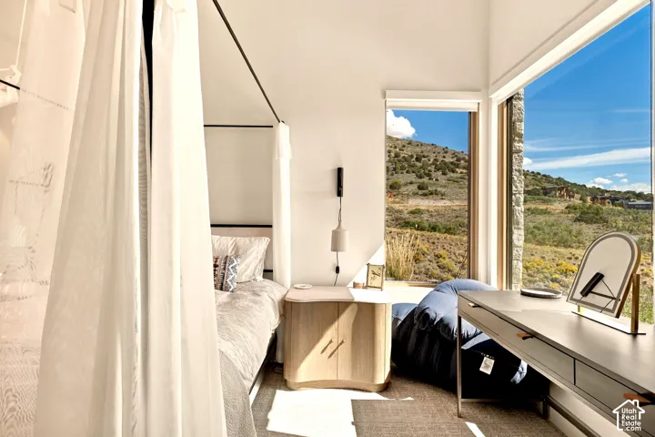 Floor-to-ceiling windows, corner window placement, built-in shelving, wood-finish flooring, and a stone exterior wall element