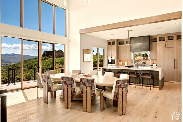 Light wood-finish flooring, soaring ceilings, and a kitchen featuring a large island with integrated seating, built-in appliances, and light wood-finish cabinetry