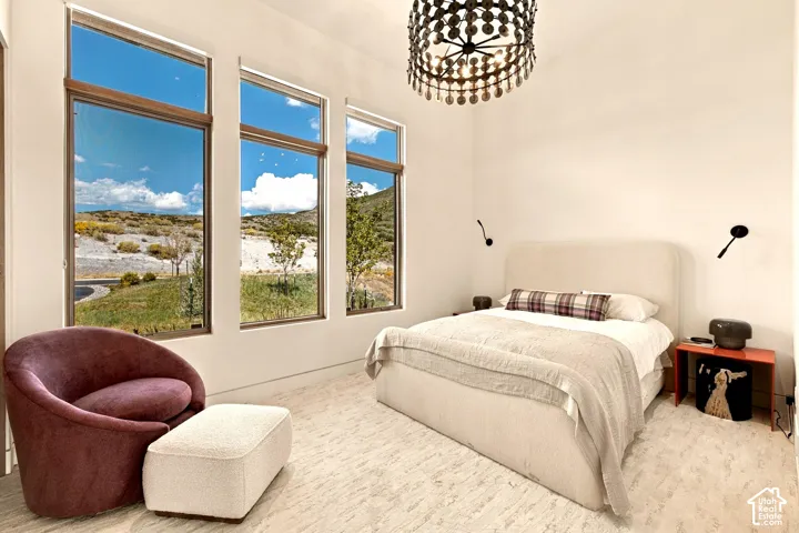 Floor-to-ceiling windows, high ceilings, large decorative ceiling light fixture, wall-mounted sconces, light-toned flooring