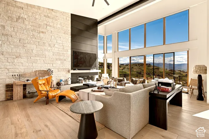 Soaring ceilings, expansive window wall, light wood-finish flooring, stone-clad feature wall, and a linear fireplace