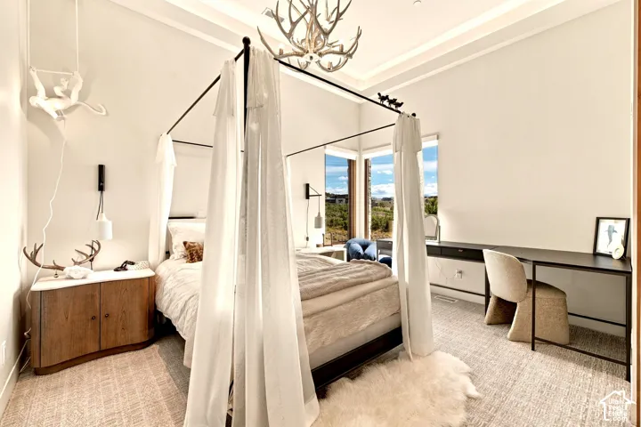 High ceilings with cove lighting detail, antler-inspired chandelier, built-in desk with integrated storage, large windows, and wall-mounted sconces