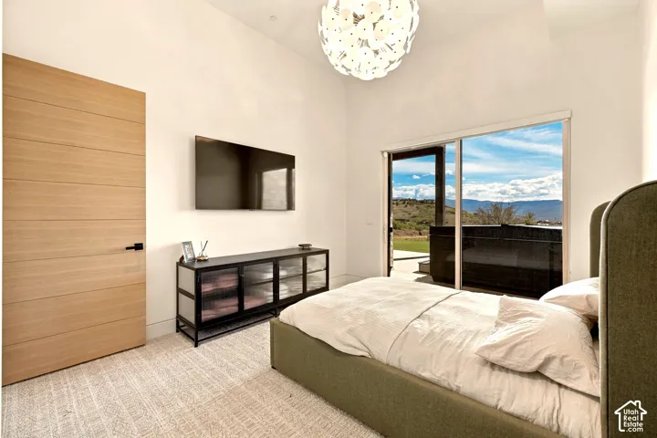 Sliding glass door leading to an outdoor area, wood-finish door, high ceilings, contemporary light fixture, and textural carpeting