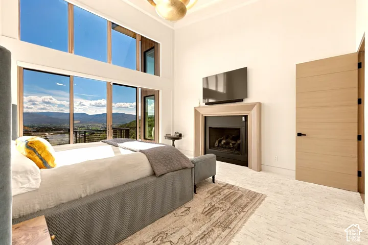 Floor-to-ceiling windows, gas fireplace, light wood-finish door, light-toned flooring, and crown molding