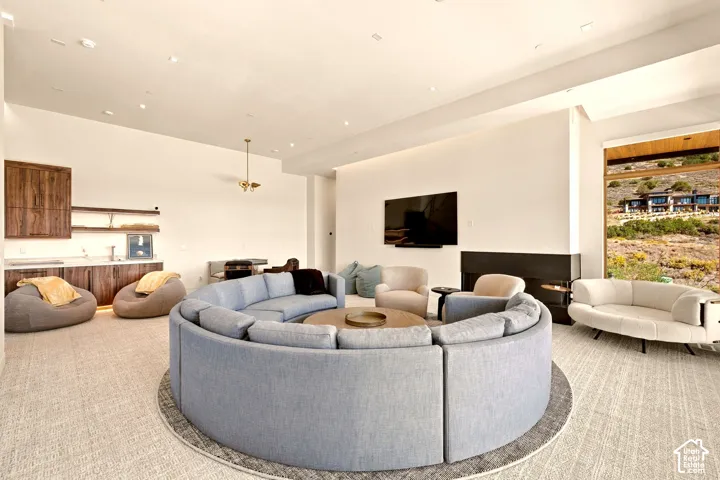 Spacious entertainment area featuring a built-in wet bar with wood-finish cabinetry, a contemporary fireplace, and a large window showcasing the mountainous landscape