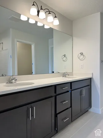 Dual vanity with dark wood-finish cabinetry, light stone-finish countertop, undermount sinks, and chrome faucets