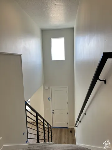 Vertical window, two-panel door, wood-finish flooring, metal stair railing, wall-mounted handrail