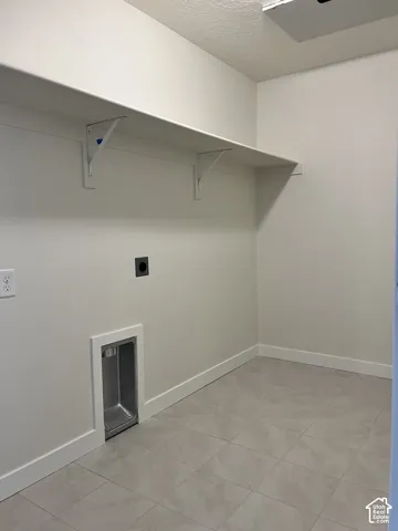 Wall-mounted shelving system, light-toned wall paint, light-toned tile flooring, and a built-in utility basin