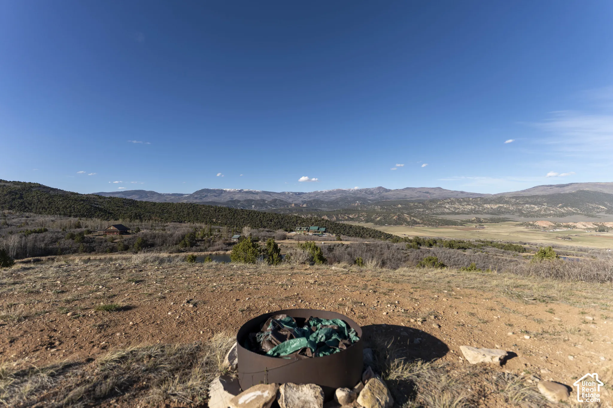 Expansive outdoor area featuring a metal fire pit, natural rock landscaping, and distant mountain ranges