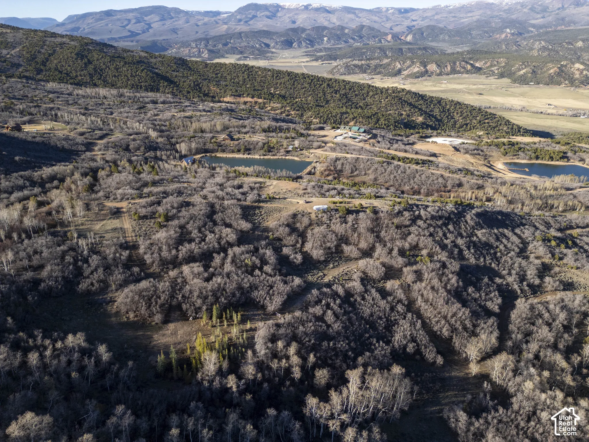 Mountainous terrain with natural vegetation, multiple ponds, and distant structures