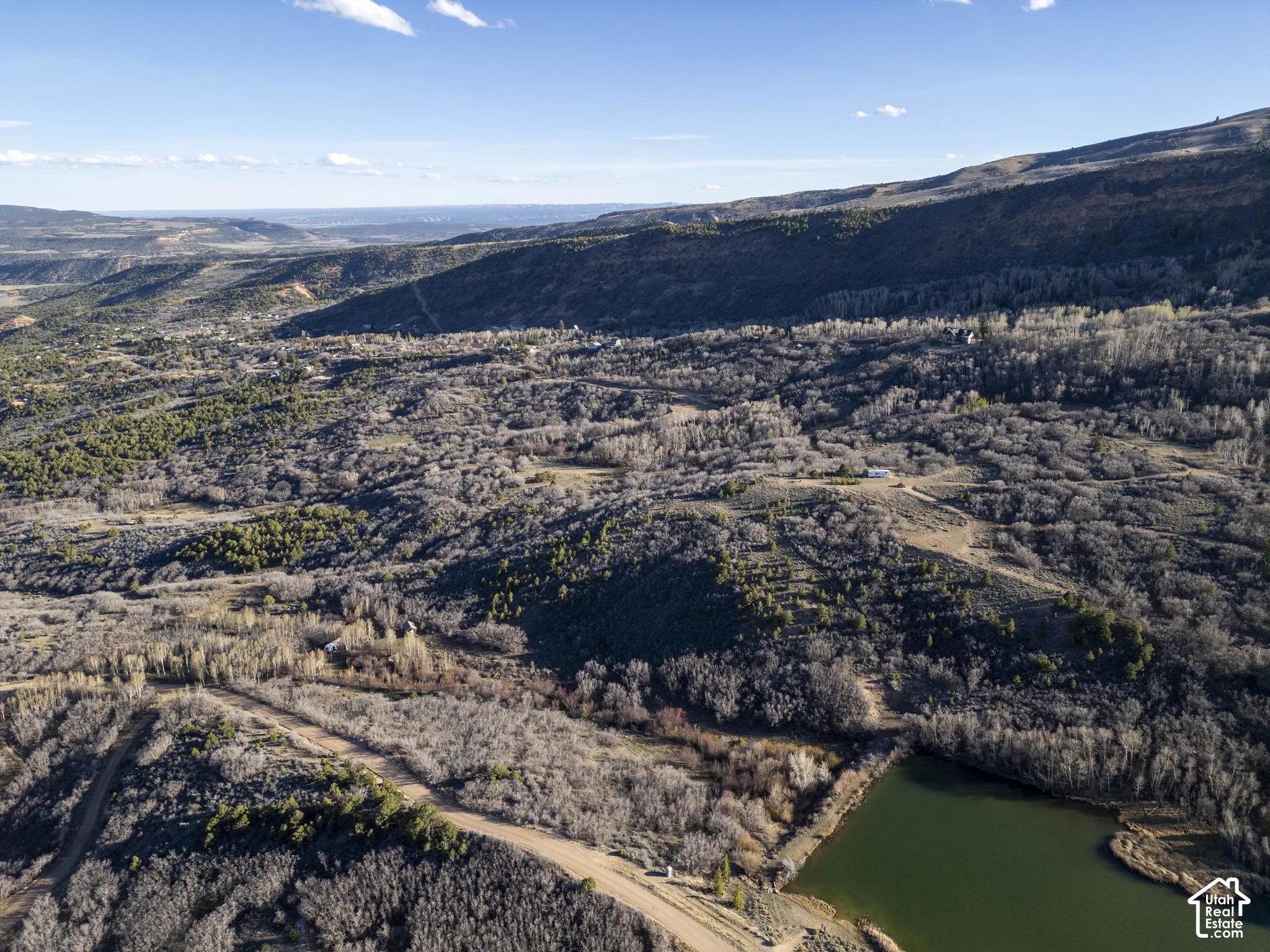 Expansive property featuring varied terrain, a natural water body, and abundant mature trees