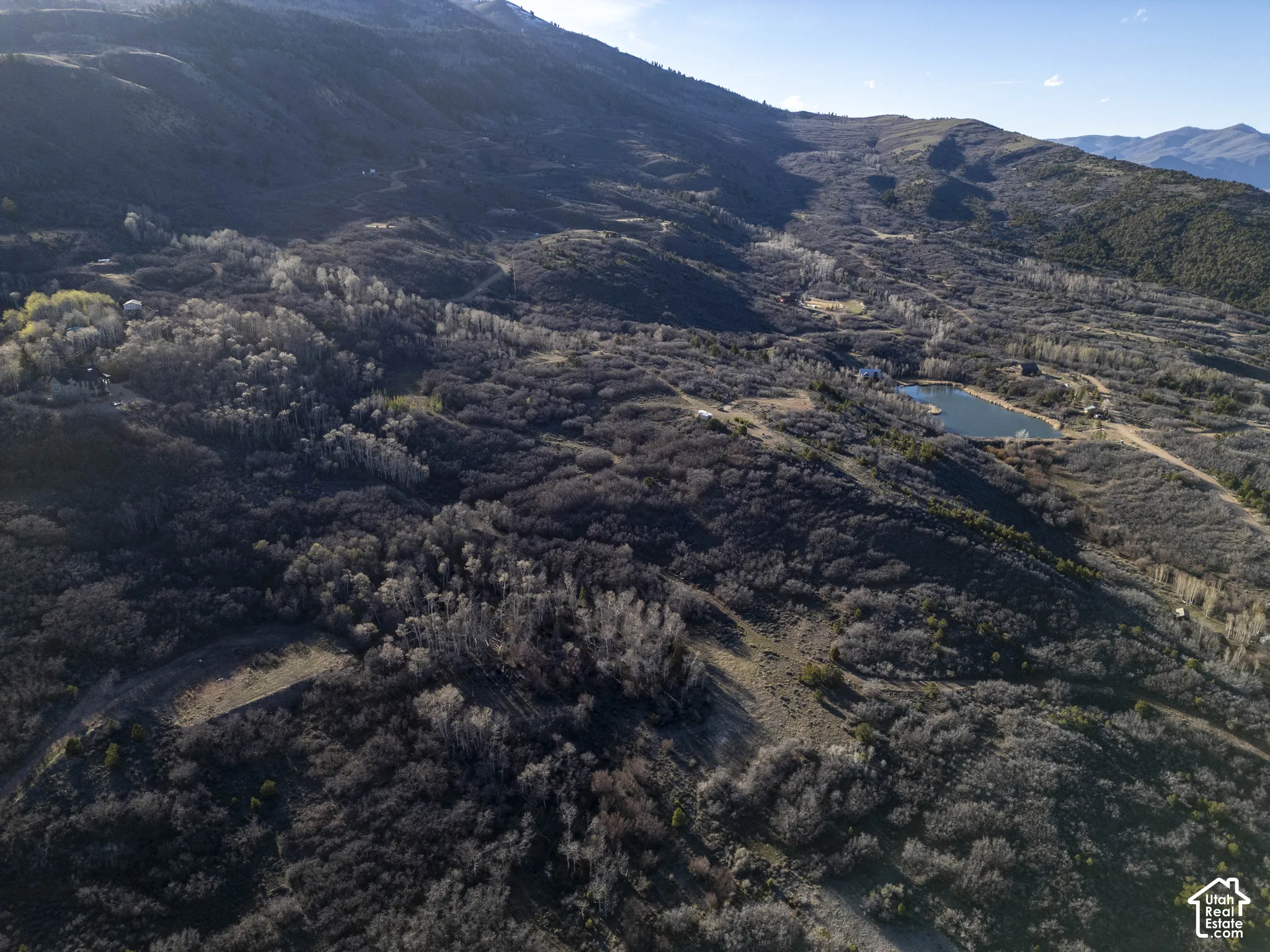 Expansive mountain landscape with diverse foliage, featuring a prominent body of water and distant mountainous terrain
