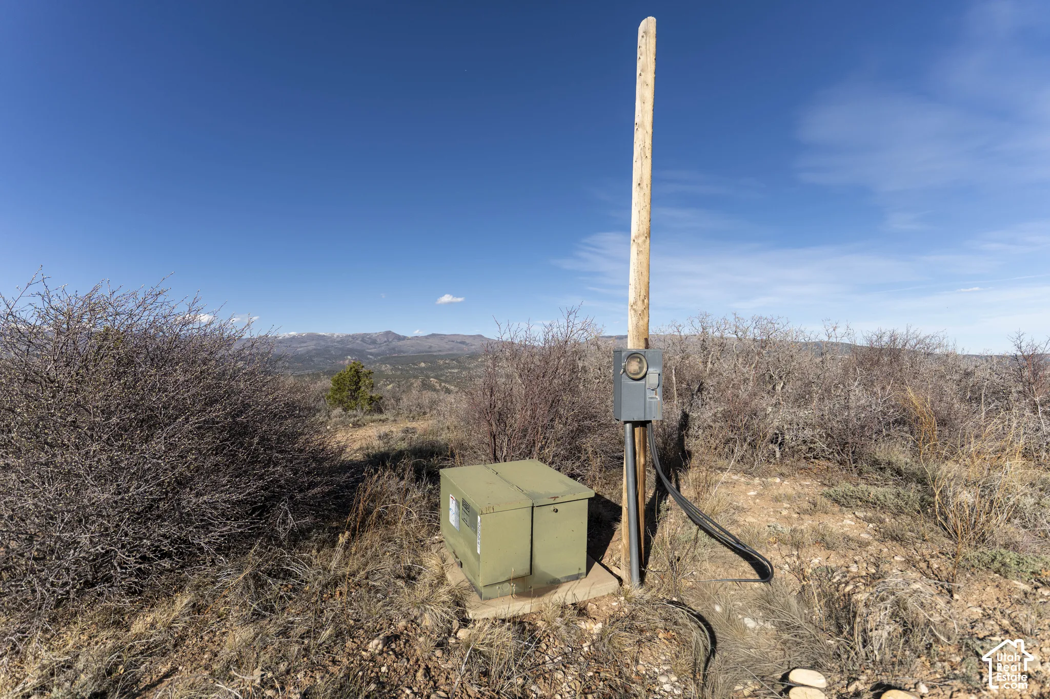 Site with utility pole, electrical meter, and service box, set against a distant mountain range