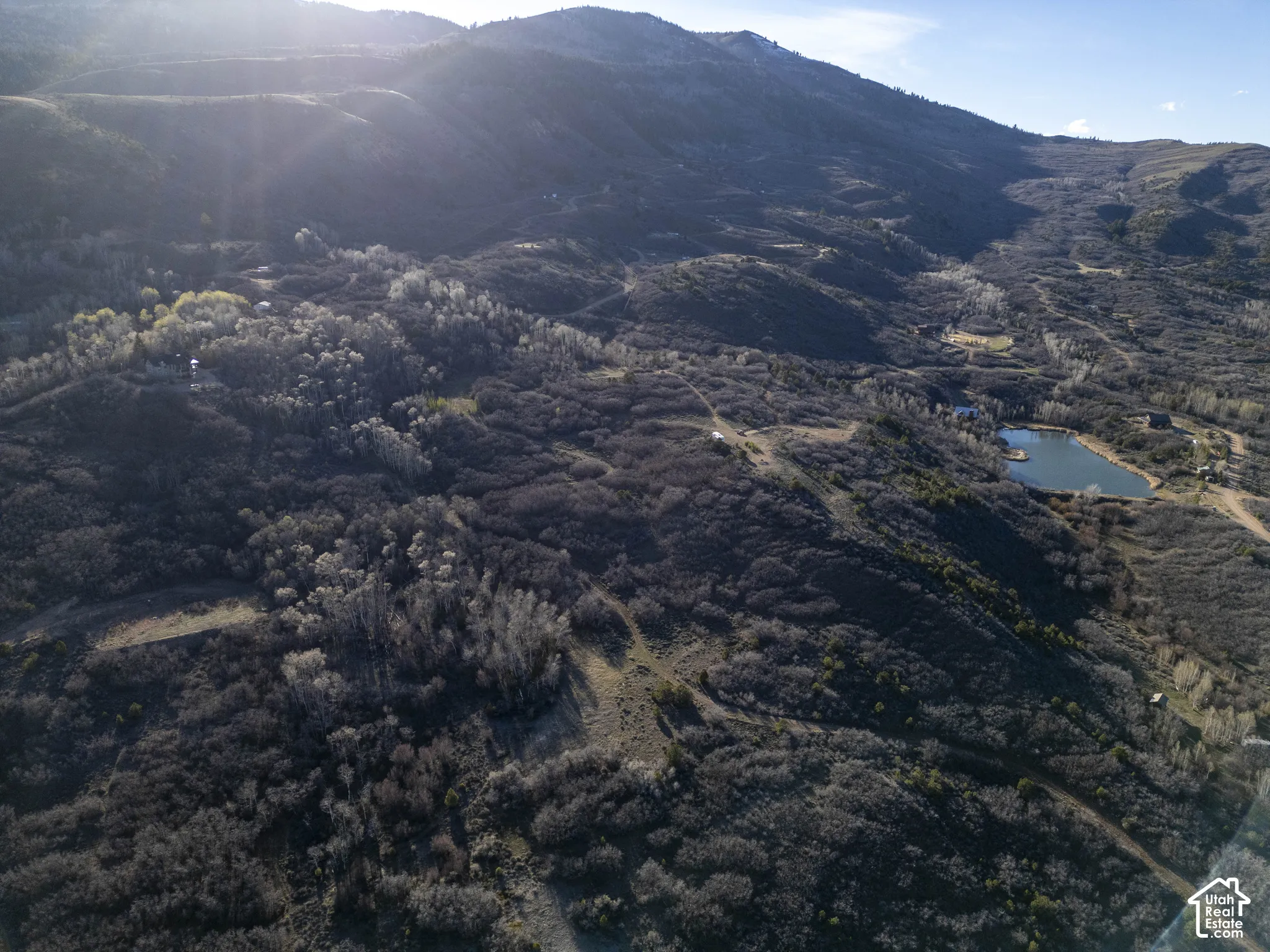 Mountainous terrain with natural vegetation, a body of water, and surrounding undeveloped land